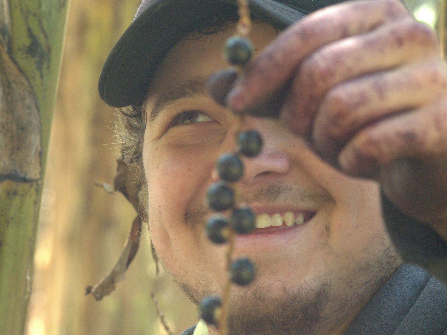 Jovem segurando cacho de açaí e sorrindo